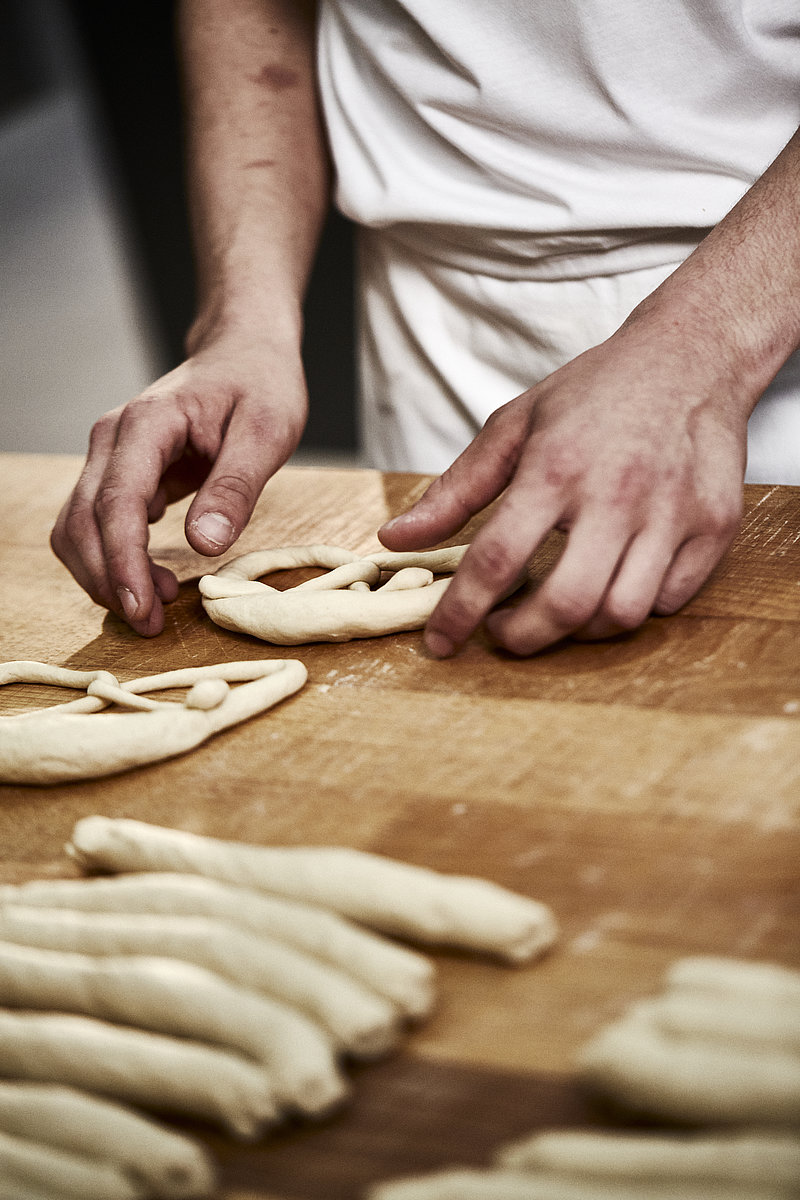 Auszubildender Bäcker formt Brezel