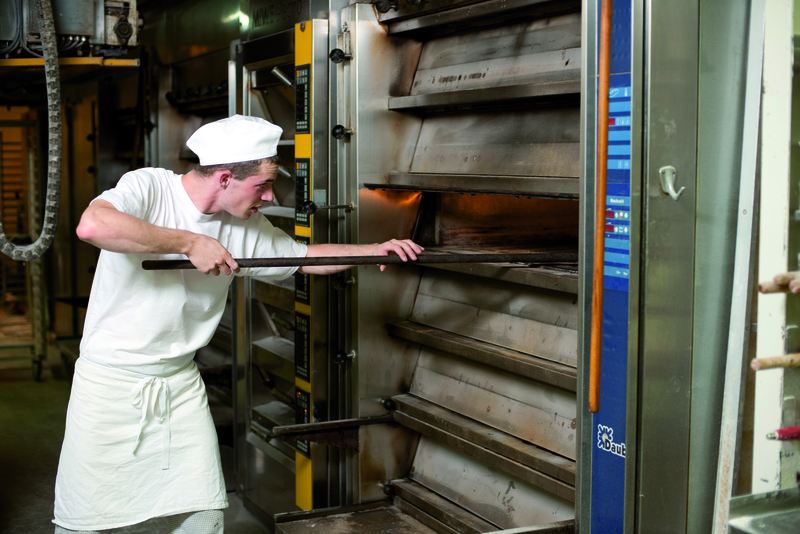 Bäckergeselle am Ofen mit Schieber