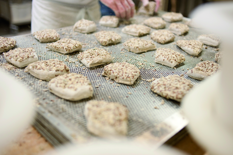 Brötchenteiglinge werden mit Körnern bestreut