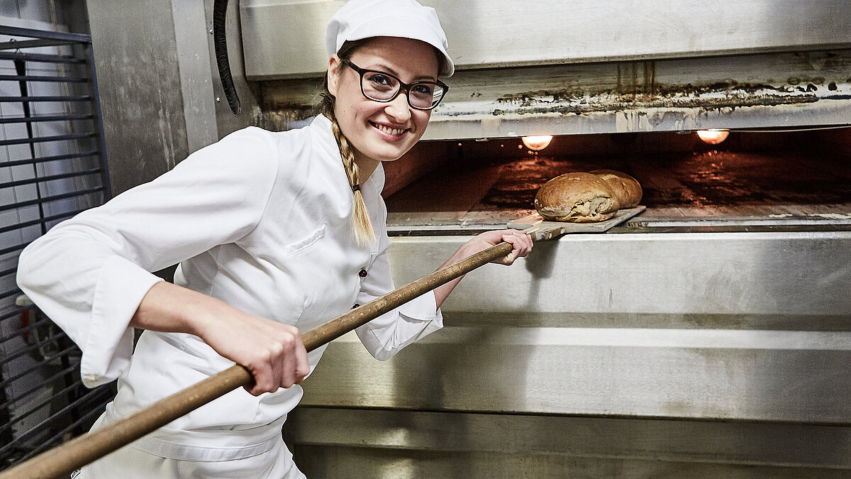 Bäckerin schiebt Brot in den Ofen