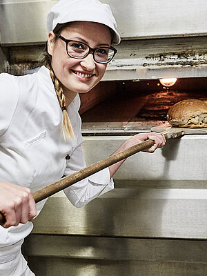 Bäckerin schiebt Brot in den Ofen