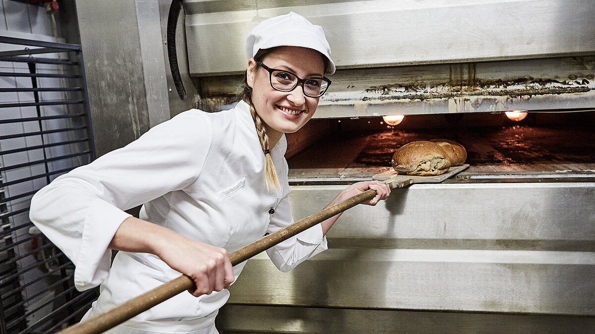 Bäckerin schiebt Brot in den Ofen
