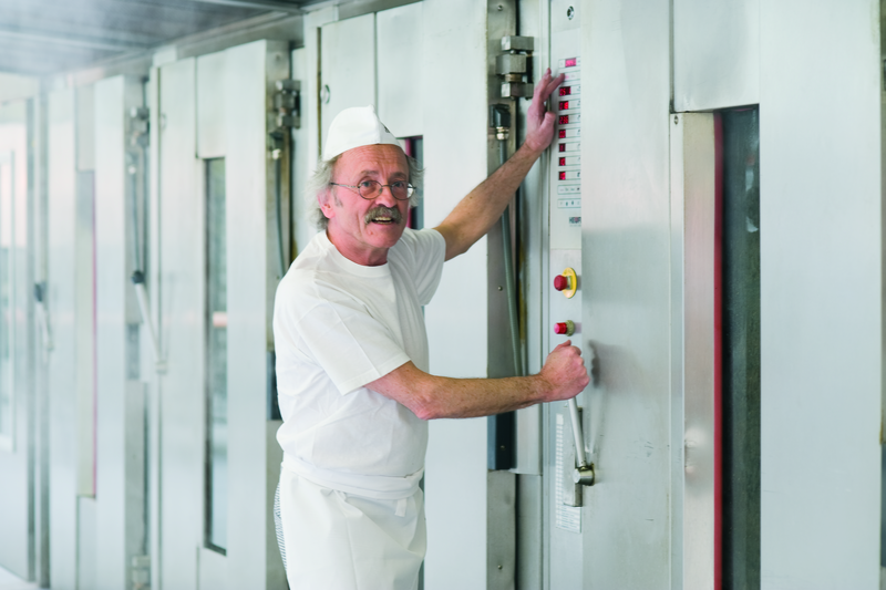 Bäckermeister öffnet einen Backofen