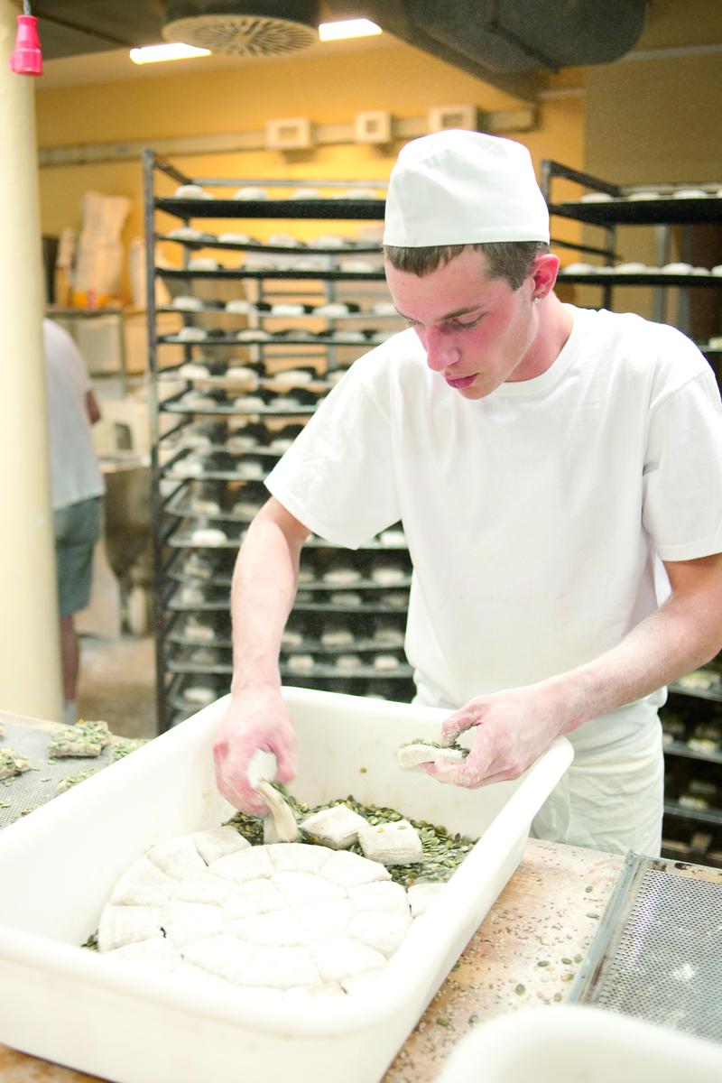 Bäckergeselle wendet Teig in Körnern