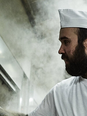 Bäcker prüft etwas am Ofen