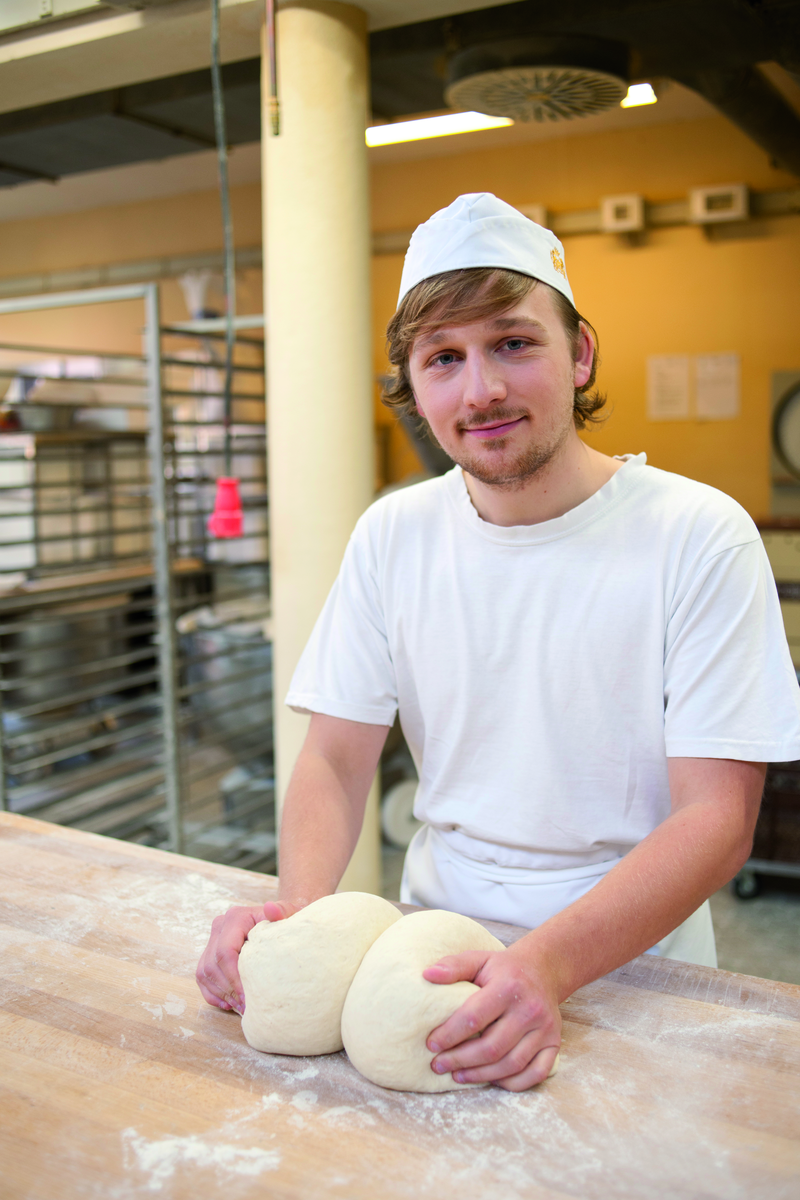 Bäckerauszubildender knetet Teig