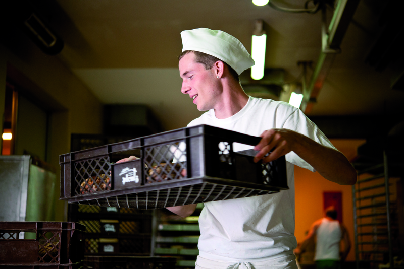 Bäckergeselle trägt Kiste mit Brot