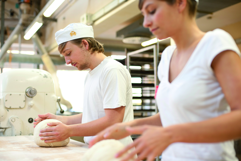Bäckerauszubildende kneten Teig