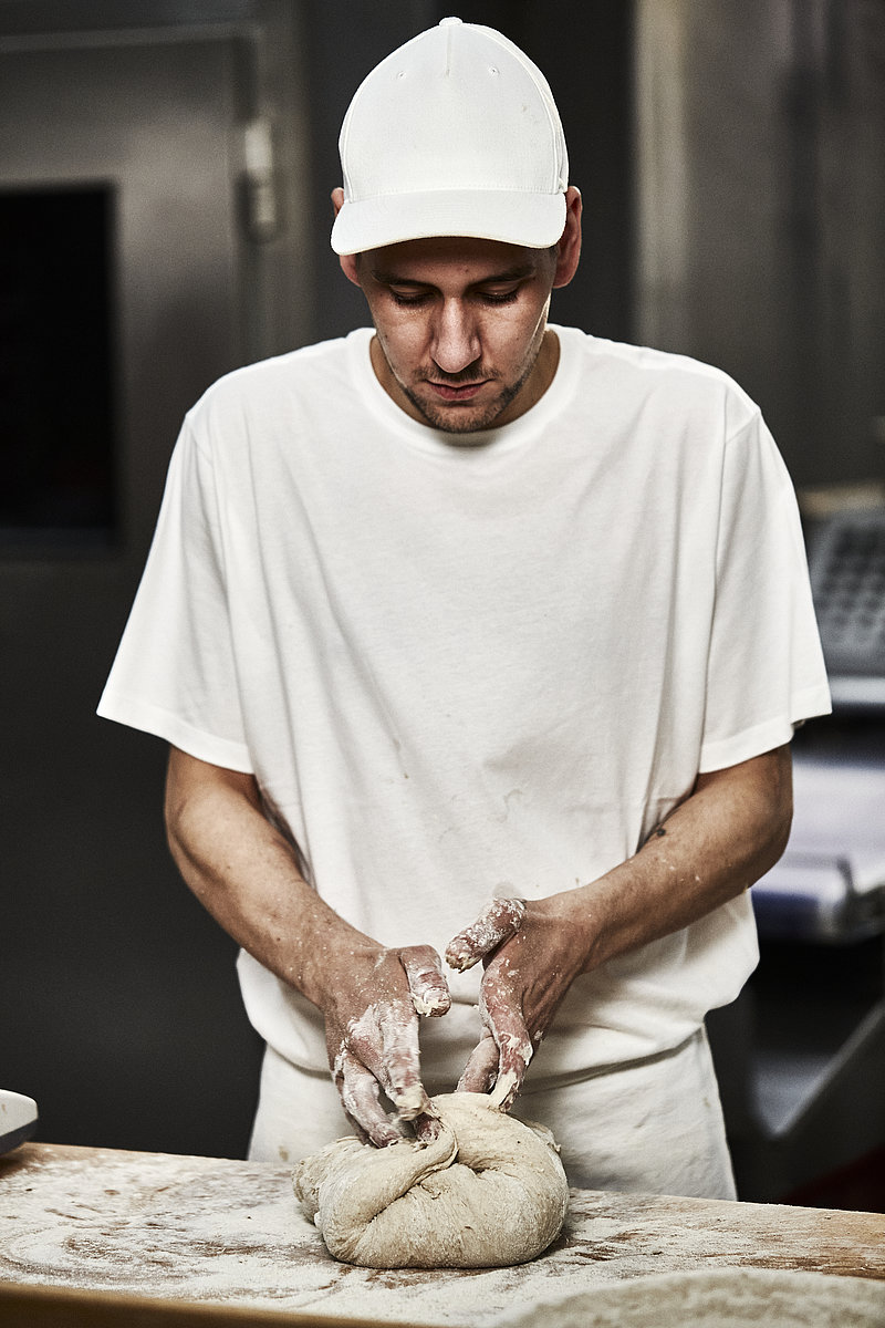 Bäcker Azubi faltet Teig