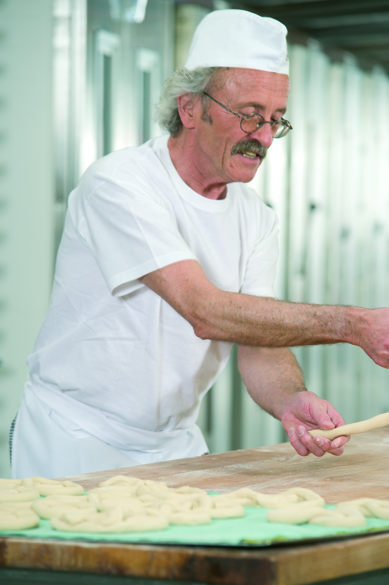 Bäckermeister formt Teig zu einer Brezel