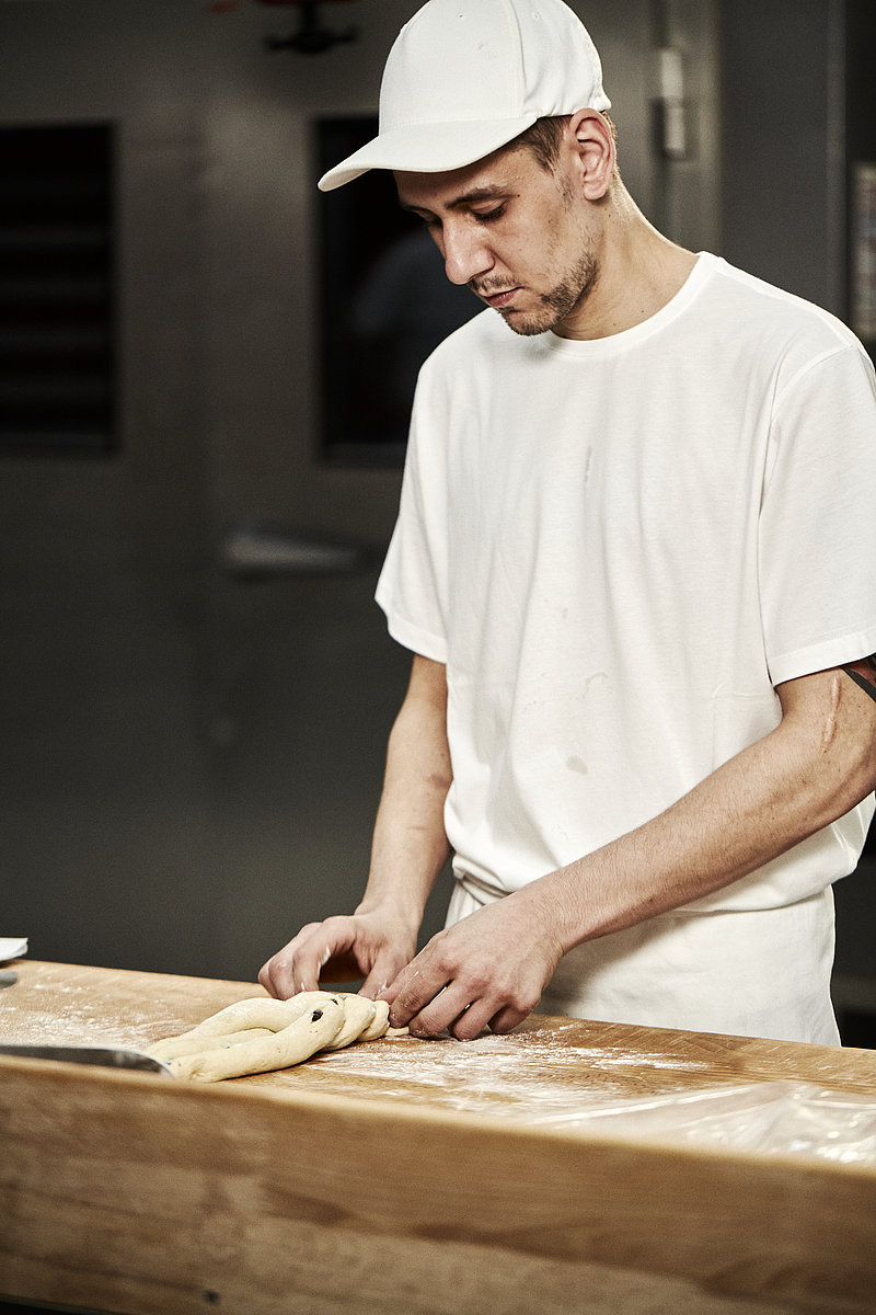 Bäcker Azubi formt Teig zu einem Zopf