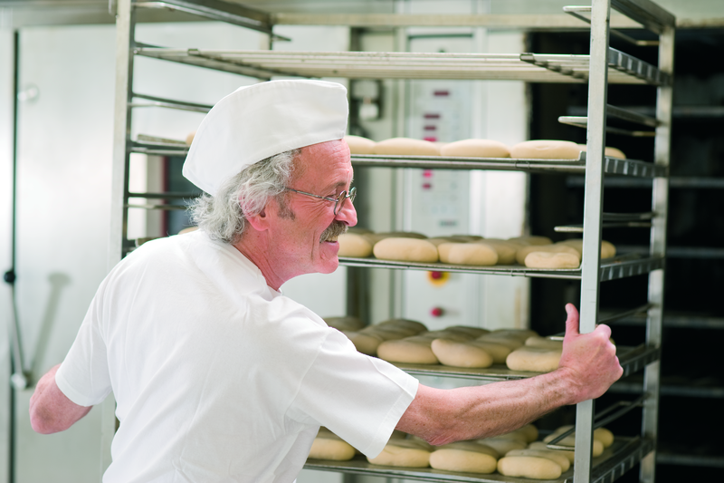 Bäckermeister beschickt einen Stikkenofen mit einem Stikken Brötchenteiglinge