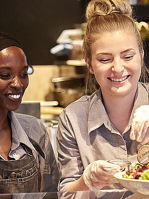 Bäckereifachverkäuferinnen an der Grillecke, bereiten ein Glas vor