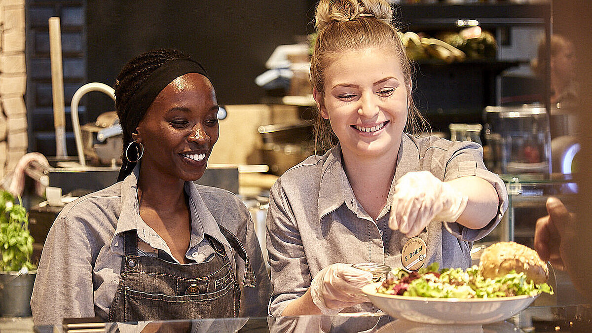 Bäckereifachverkäuferinnen an der Grillecke, bereiten ein Glas vor