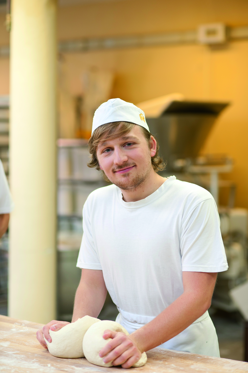 Bäckerauszubildender knetet Teig