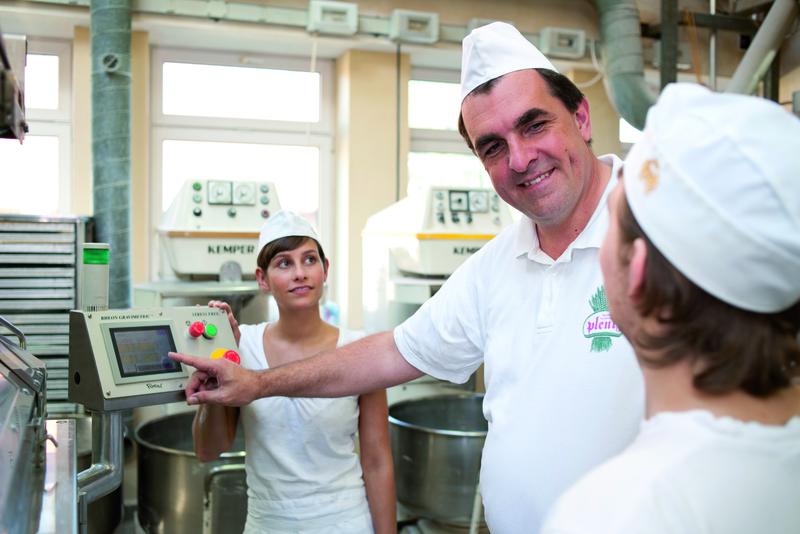 Bäckermeister erklärt Azubis Maschine in der Backstube