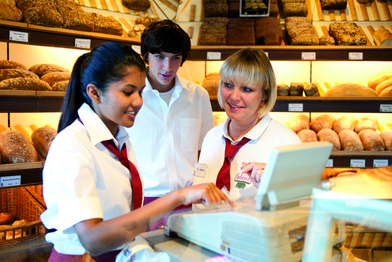 Verkäuferinnen sprechen mit Auszubildendem
