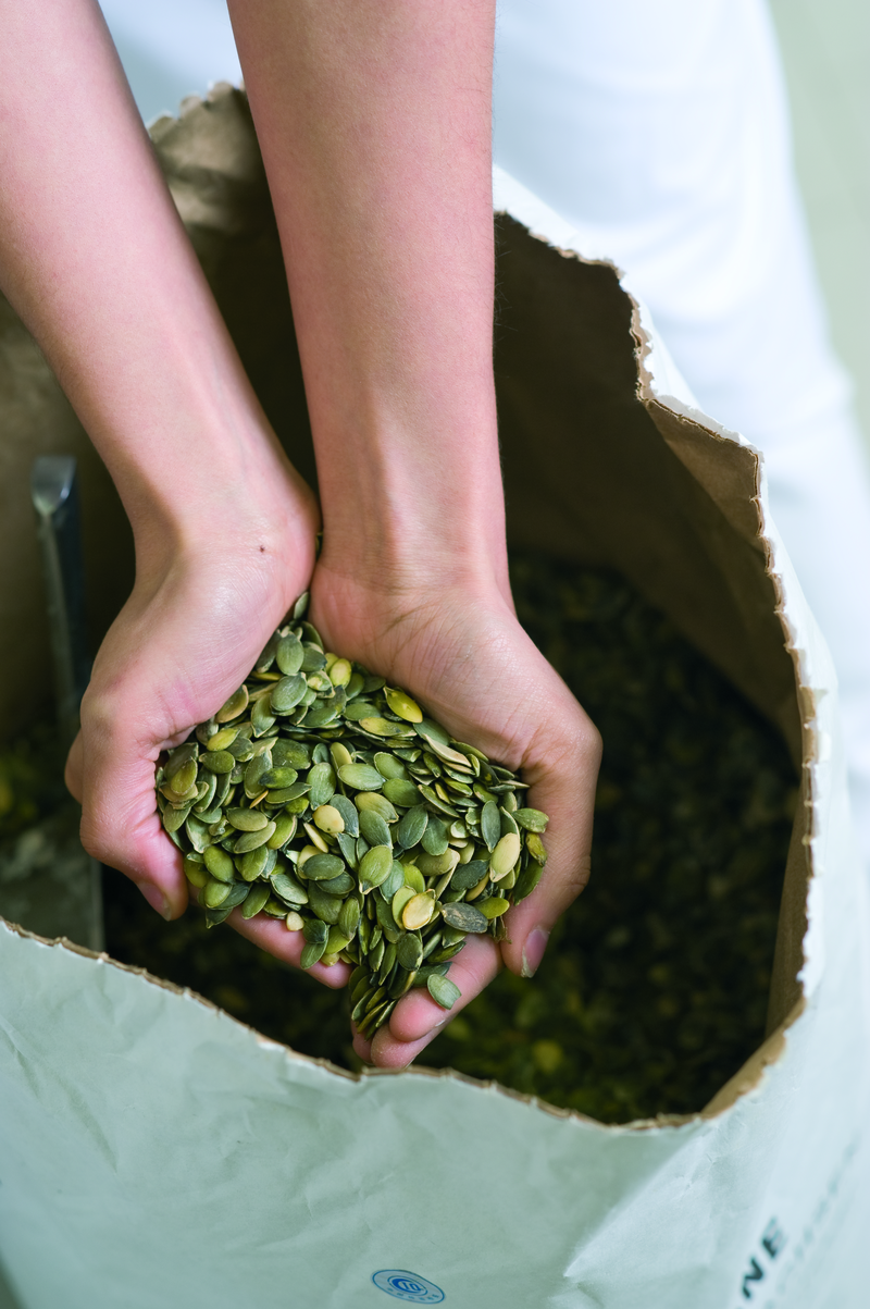 Hände nehmen Kürbiskerne aus einem Sack